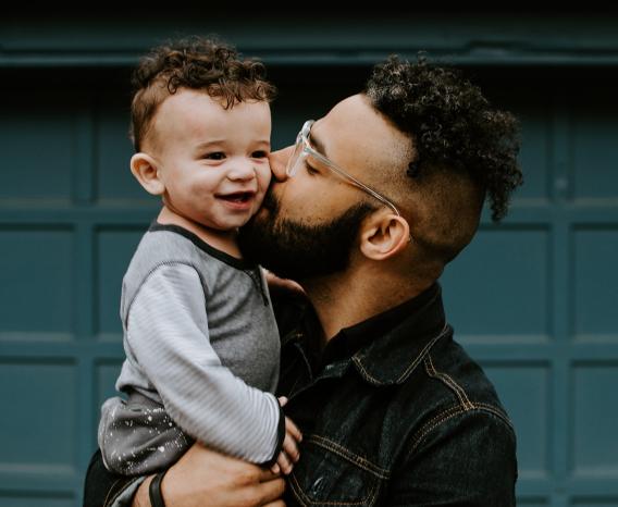 Man kissing toddlers cheek.
