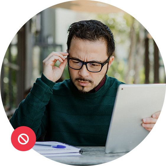 Man looking confused while adjusting glasses and reviewing a tablet and documents.